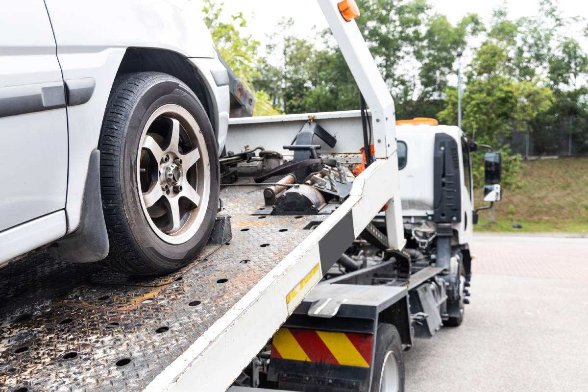 Cable attached to broken down car being pulled onto flatbed tow truck