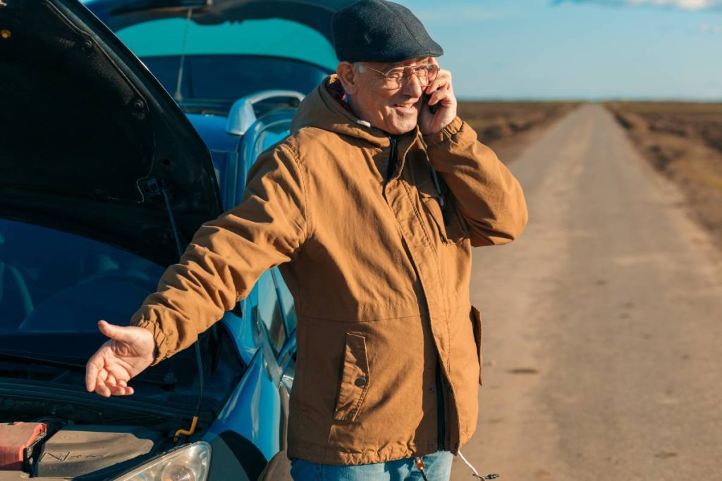Senior man on the road having engine failure, he is calling for assistance.